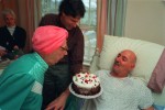 A resident presents a cake to a fellow resident on his birthday, one of many he has celebrated since being told he had only six months to live.