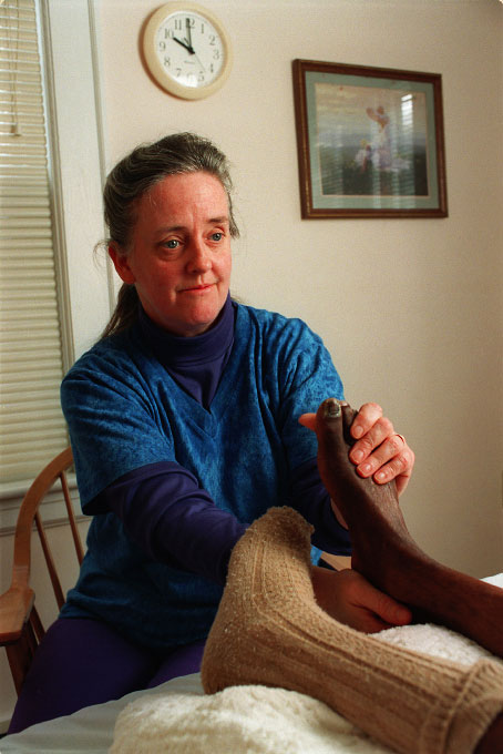 Maureen, a hospice nurse, massages the foot of a patient with AIDS.