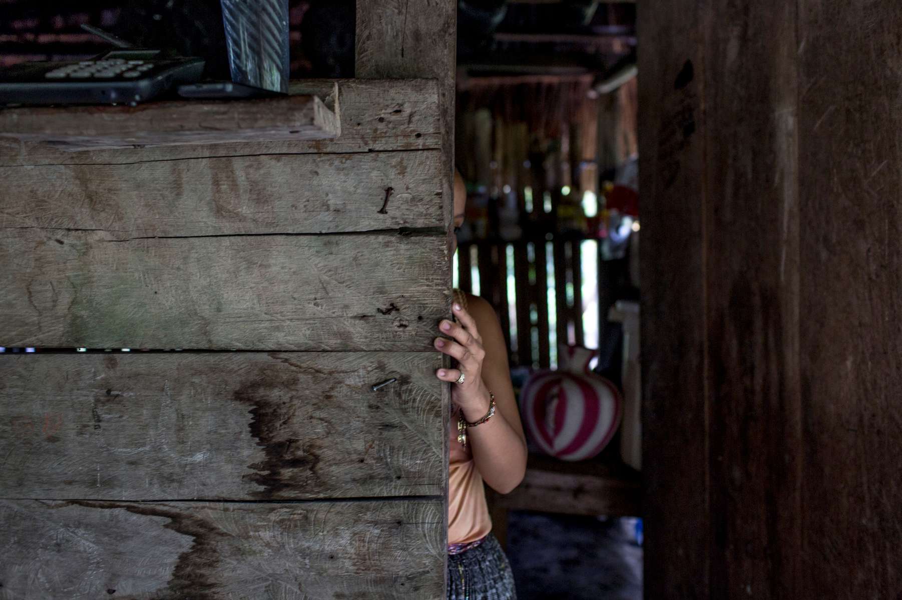 EL ESTOR, GUATEMALA. February 12, 2018 – An indigenous Maya Q'eqchi woman at home in a community in the Polochic Valley, Guatemala. Her family have received threats from their neighbors because her father works for a banana and palm oil company, which many do not agree. However, his employment has helped the family, they have a larger home, and small plot of land, and better living conditions than most in their community.