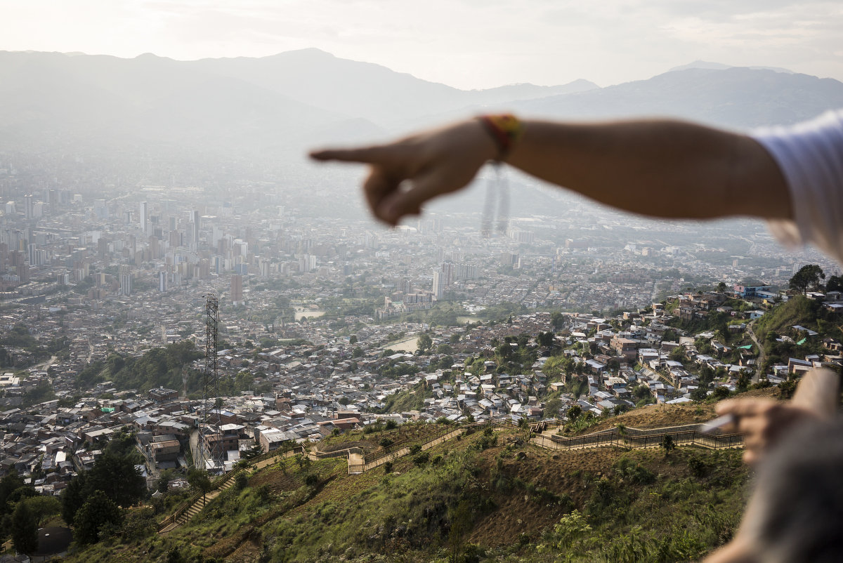 A view of Medellin, Colombia from the top of Comuna 8. The city is building a 46-mile long concrete bike/walk {quote}greenbelt{quote} surrounding the entire valley intended to curb urban sprawl. However the residents of the top of Comuna 8 say that the city basically poured concrete over an existing path created by them. {quote}The concrete makes your feet more tired then the dirt path,{quote} said one resident. Many residents are displaced campesinos from the half-century long conflict.