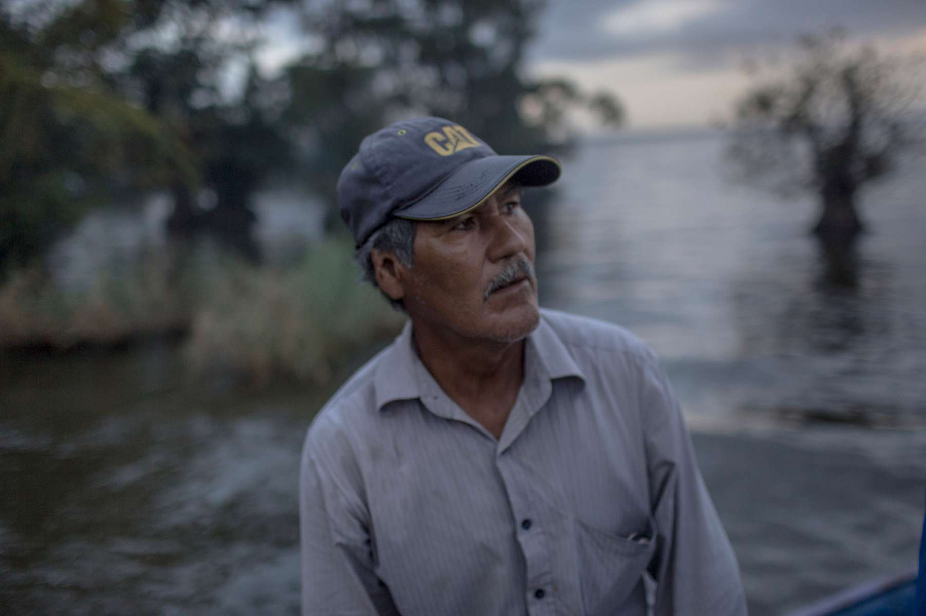 IZABAL, GUATEMALA. Februrary 13, 2018 – A boat driver waits for passengeres to cross Lake izabel. Indigenous Maya Q'eqchi communities such as Chapin Abajo along Lake Izabal in eastern Guatemala, have no state presence. Only a palm oil company provides jobs and health services. In the last 20 years, palm oil plantations in the region replaced former cattle ranches but it has exacerbated the struggle for land rights in the Polochic Valley. Guatemala has the second-largest rainforest cover in Latin America, after Brazil. The country lost an average of 68,000 hectares a year between 2005 and 2010 (3.72% per year). The rate of deforestation has almost tripled in a decade due to government regulations that incentivize productive lands over natural areas and promote subsidized development.