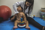 MARCH 15, 2017 -- Physical therapist Mayra Barata works on Baby Duda's posture at a physical therapy session at Oswaldo Cruz University Hospital, in Recife. Miriam and Cleane waited nearly 3 hours this session. They arrive early to be the first in line to meet with therapists. During this time, they catch up with other mothers who have children with zika-related microcephaly, and share their knowledge and discoveries as their babies encounter changing health issues. They talk about the latest concerning issue now, hydrocephaly - when there's too much water in the brain.