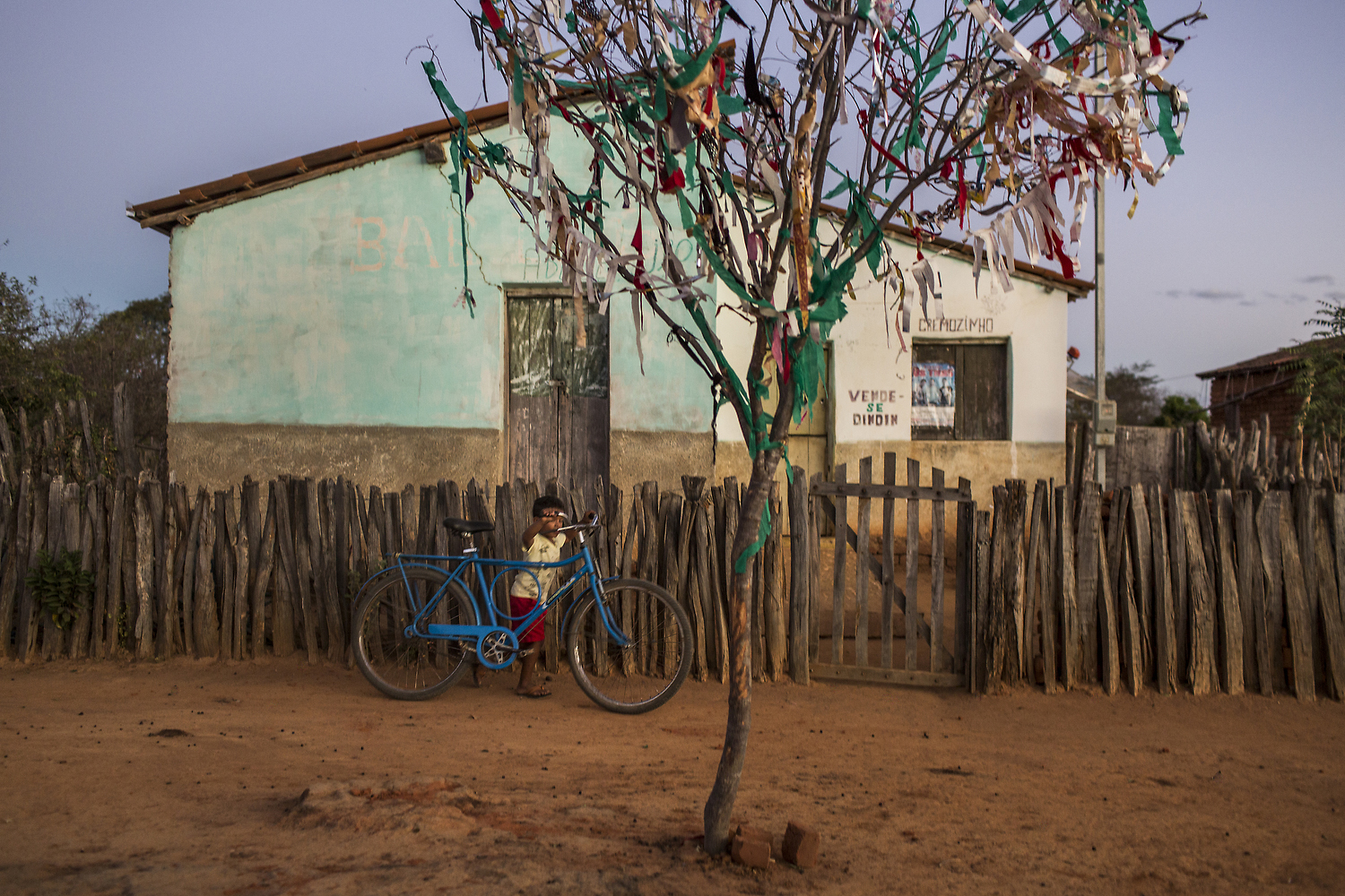 A boy walks a bike in the Sertão, a semiarid region in Northeast Brazil, where its people and land are shaped by years of relentless drought and social exclusion. Bahia, Brazil. 2015.Details – Handsigned. Open Edition. Medium: Archival pigment print. Paper: Pro Luster. Image Size: 8 x 10-inches, unframed. $135