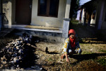 A woman sifts through dirt, pulling weeds in front of her new home which was built by the Irish Red Cross, in Banda Aceh, Indonesia, on Tuesday, Nov. 17, 2009. Although Aceh is a matriarchal culture, women who break Sharia rules are often stigmatized, and often become objects of harassment. 