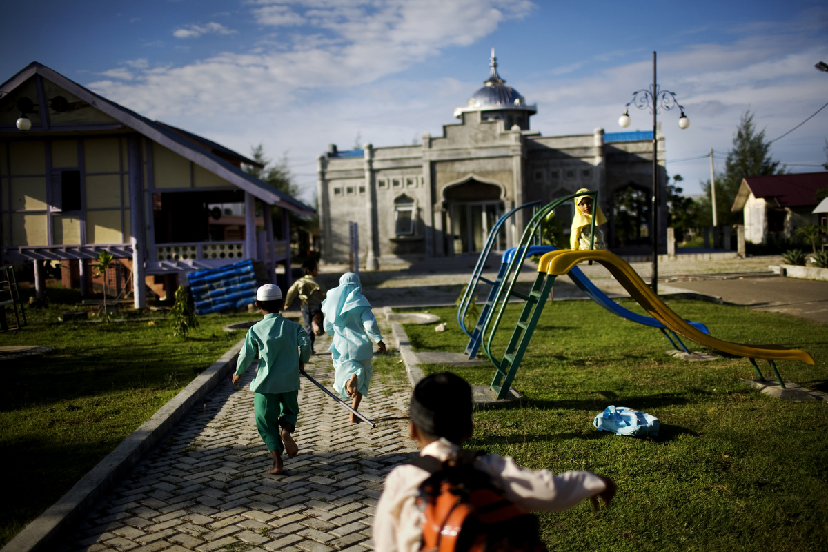 Children run to a newly built mosque in their neighborhood, in Banda Aceh, Indonesia, on Tuesday, Nov. 17, 2009. The neighborhood was devastated by the tsunami, killing most of the residents. Most of the homes here have been rebuilt by the Irish Red Cross. On Dec. 26, 2004, a 9.0 magnitude earthquake triggered a massive tsunami that killed 226,000 people throughout several countries. In Aceh, the death toll alone was 166,000. 