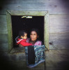 A woman with her grandson in the window of her wooden home, in a remote village outside of Uspantan, Guatemala, on March 28, 2012. Many indigenous Guatemalans were accused by the government of harboring leftist guerrillas. Villagers here fled to the mountains where they lived for 12 years when the military came and burned their homes, raped the women and forced men into civic patrols. 