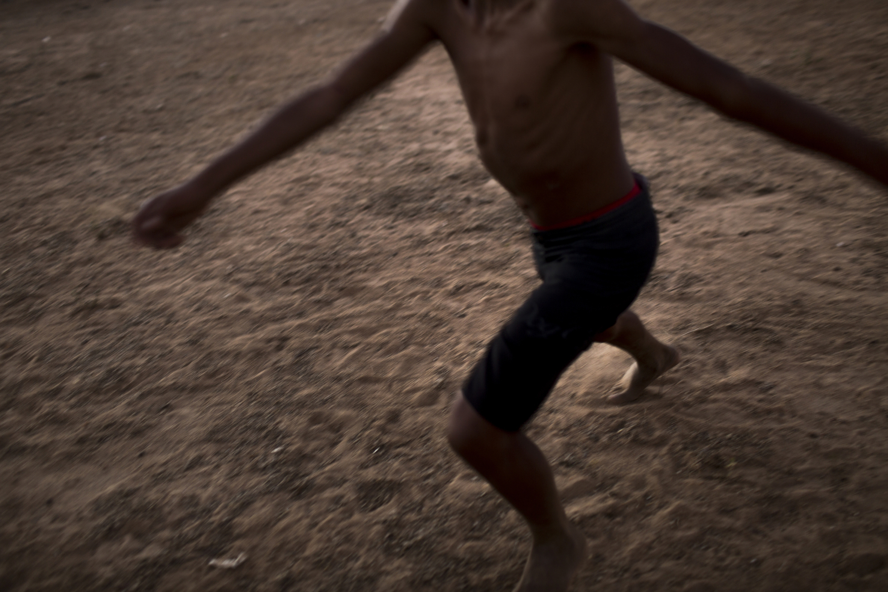 Sobradinho Reservoir, Brazil. Monday, July 20, 2015. A youth plays soccer on a dirt pitch at dusk, near the Sobradinho Reservoir, Brazil. 