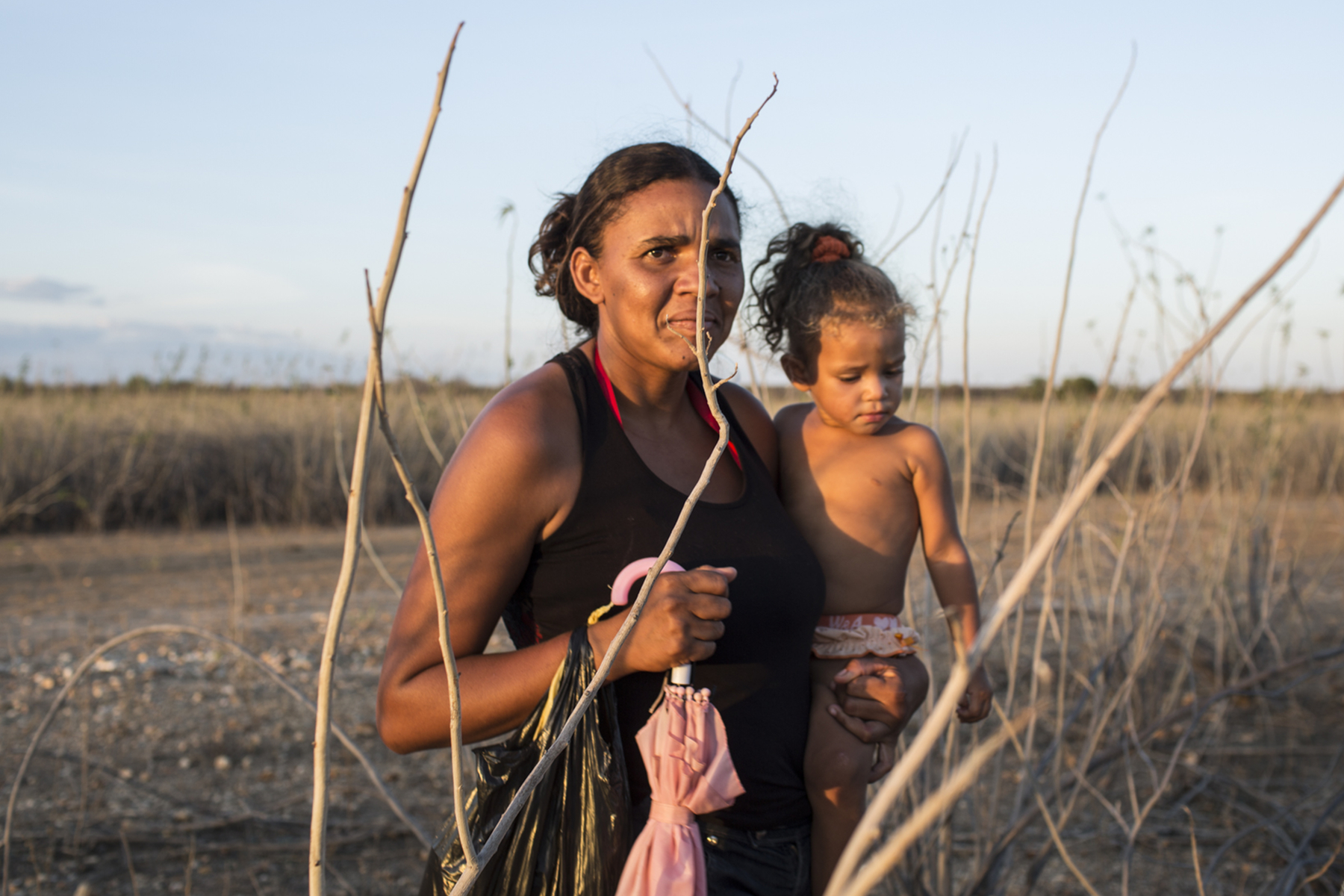 Passagem, Bahia, Brazil, on Wednesday, Nov. 11, 2015.A woman carries a child through a dry tributary of the Sao Francisco River after her community held a spiritual event to pray for rain, in Bahia state.