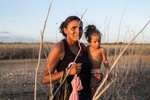 Passagem, Bahia, Brazil, on Wednesday, Nov. 11, 2015.A woman carries a child through a dry tributary of the Sao Francisco River after her community held a spiritual event to pray for rain, in Bahia state.