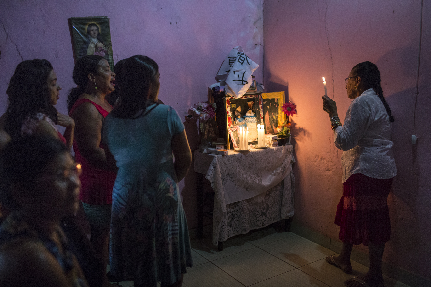 Campo Alegre de Lourdes, Bahia. Tuesday, Feb. 9, 2016.Dona Maria de Lourdes da Silva, 75, right, sings prayer songs and gives thanks for the return of her figurines, Saint Antonio (St. Anthony is the Patron Saint of Lost Things and Lost Souls) and Sagrado Coraçao de Jesus (Sacred Heart of Jesus which represents divine love), with her neighbors at her home, near Campo Alegre de Lourdes, in the state of Bahia. During intense droughts, families engage in a unique ritual. They 'steal' one another’s saint figurine, called {quote}Rouba do Santo,{quote} or rob the saint. The return of the Saint to the owner is called {quote}Levada do Santo,{quote} or return the saint. Families practice this ritual to invoke rain to fall. When a Saint goes missing, the power of faith by the owner of the Saint prays immensely for the rain to come. When the rains come, the Saint is then returned. If the rain doesn’t come, the Saint remains missing.Seven days after Dona Maria’s Saint went missing, the rains came and stayed for a month. It was the first significant rain in about six years.