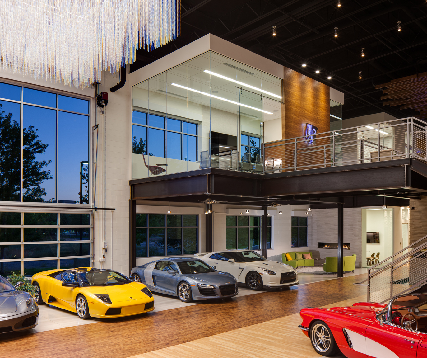 Commercial Office Studio featuring car collection with Corvette, Ferrari and Porche. Photo includes large windows with dusk light and second level conference room all with a modern style. 