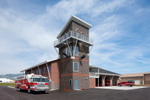 Exterior view of fire station with fire men rapelling from tower.Architectural Photography by: Paul Richer / RICHER IMAGES