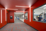 Interior photograph of long red hallway at Bio Fire, a bio tech company in Salt Lake City, Utah, with horizontal and vertical strip lighting on the ceilings and walls. The hall also has windows alloing for transparency into the lab spaces. 