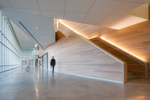 Motion blur of man walking down well lit corridor with large glass windows and sleek wooden stairwellArchitectural Photography by: Paul Richer / RICHER IMAGES