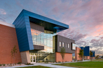 Exterior view of classroom wing at sunrise at Mt. Jordan Middle School in Sandy Utah for MHTN Architects / Hogan & Associates. These wings feature metal cladding and overhangs of blue metal. Architectural Photography by Paul Richer / RICHER IMAGES