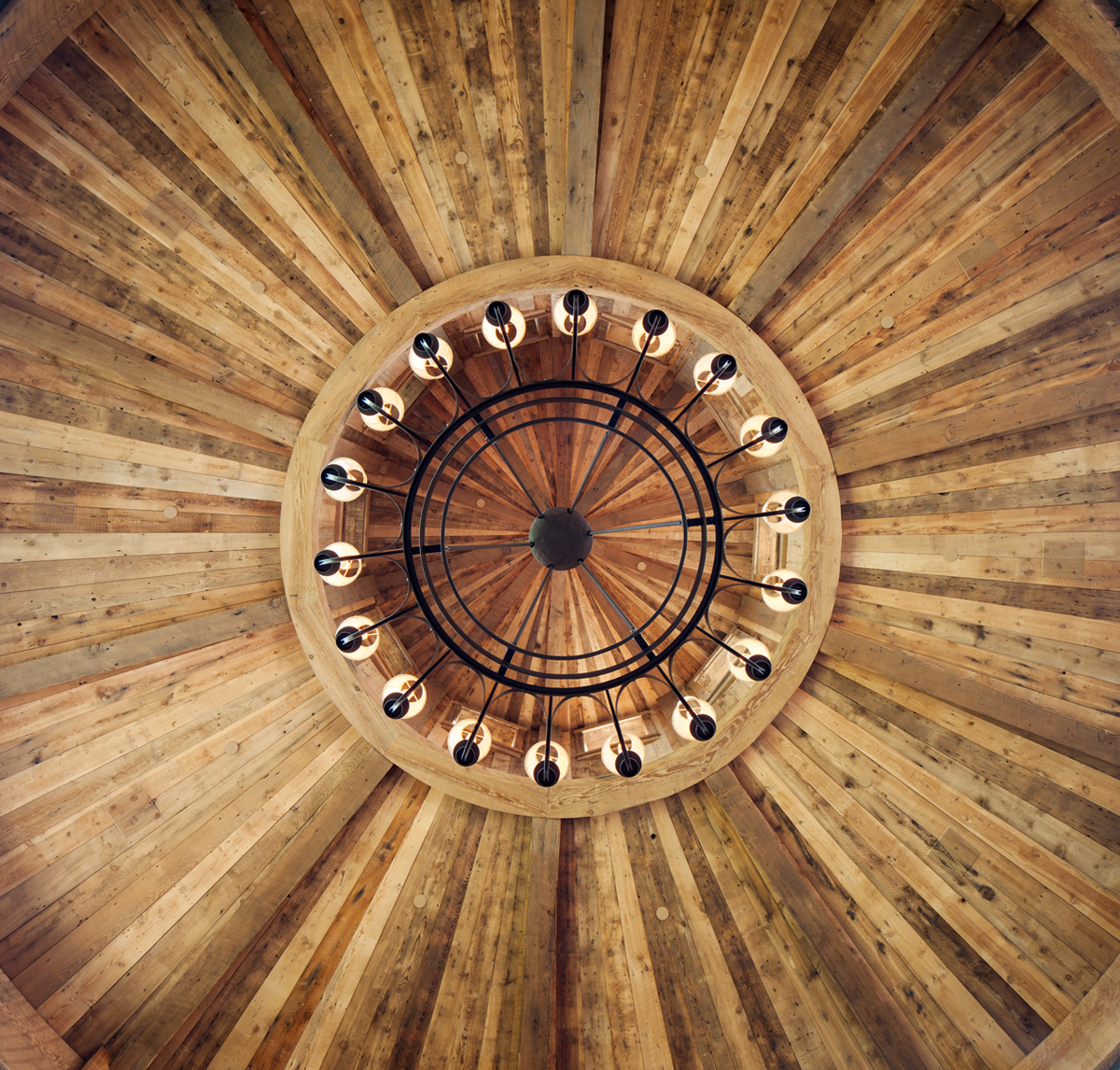 This is an interior detail of the rotunda of raw and reclaimed timber and the chandeleir in a private residence is the Shooting Star Development in Jackson, WY.