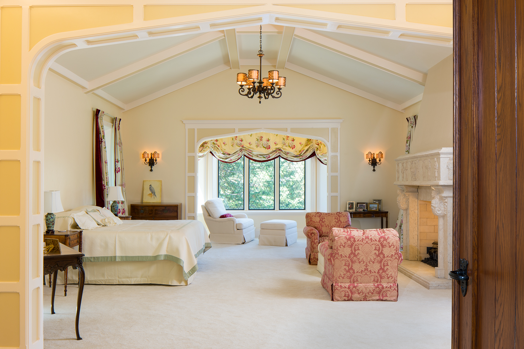 Master bedroom in a Scottish manor house with vaulted ceilings and a a large stone hearth and mantle.