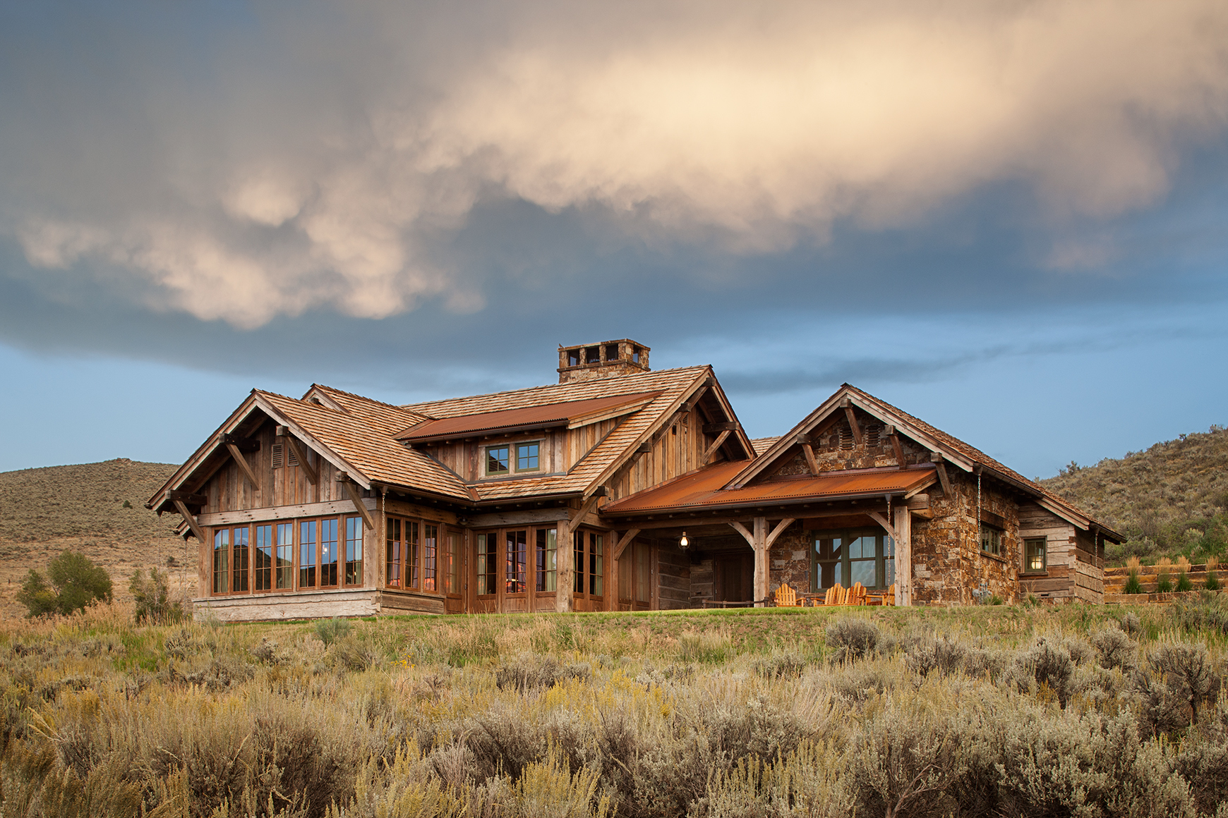 This is an exterior view of a rustic home with reclained timbers amidst the sage brush of Park City, UT. The photo was taken in late afternoon and has very dramatic clouds over head.