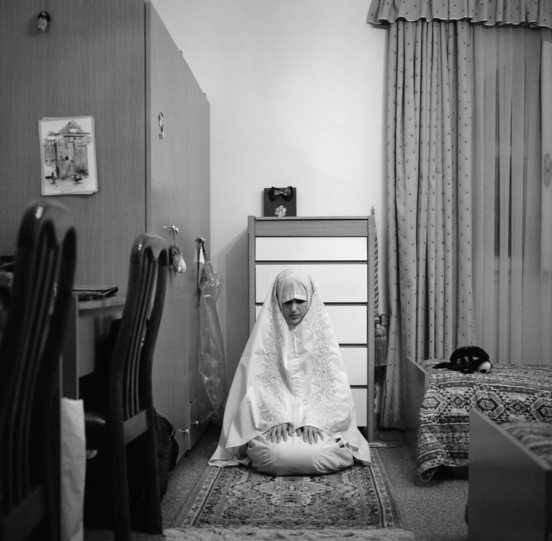 A Libyan woman prays in prayer garments in her bedroom. When Muslims pray they present themselves to God in the act, to be fully covered is a mark of respect. Muslim women are required to dress modestly as required by the Holy Qur'an. Women are not required to wear prayer attire unless their clothes are tight.