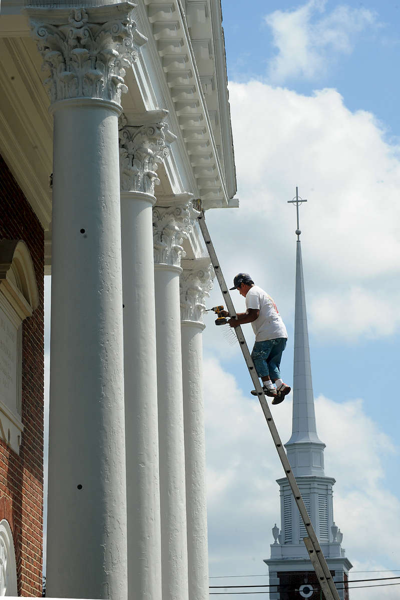 Sergio Ramirez of Painter's Pride works on the columns at the First Parish in Framingham. The meeting house was refurbished after a year long fund raising effort.  The steeple pictured is from the Plymouth Church across the street.Daily News Staff Photo/Art Illman