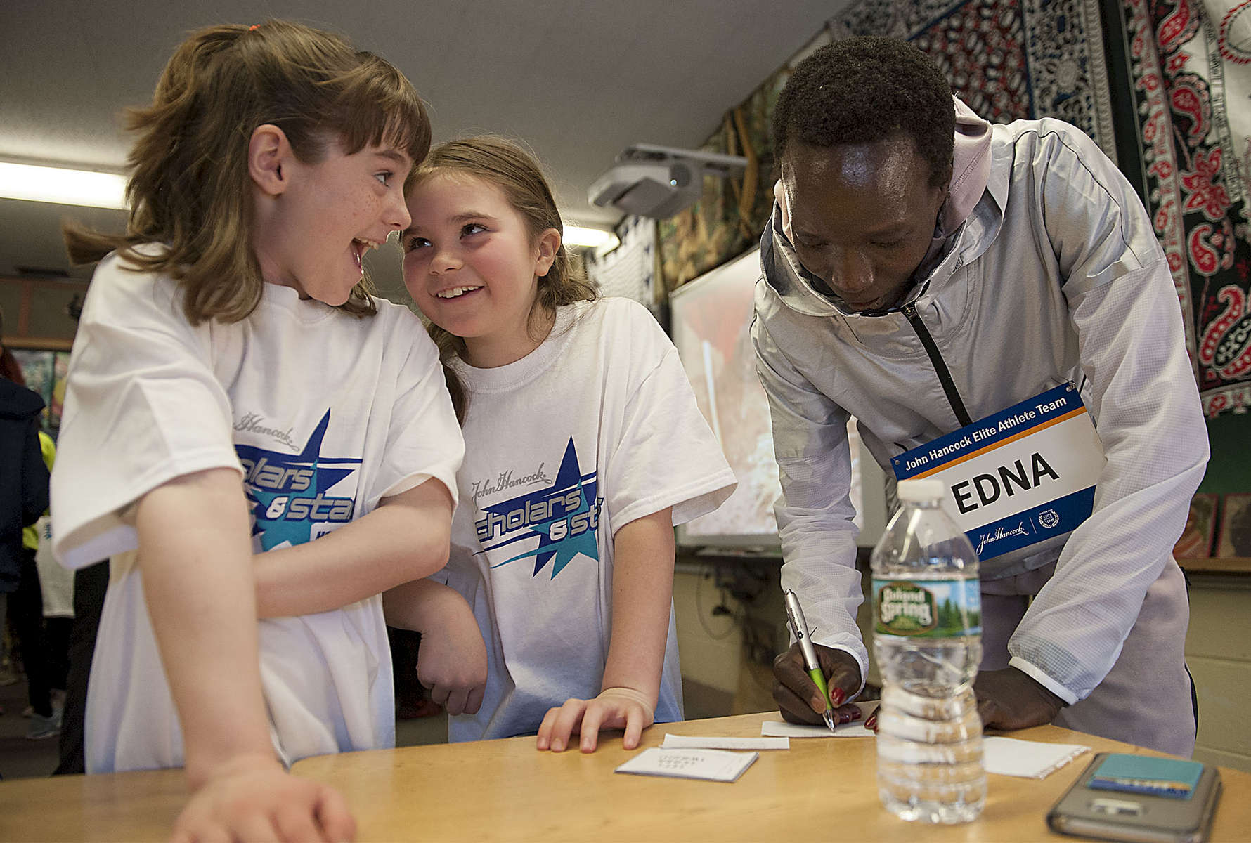 4/11/19-- HOPKINTON-- At the 27th annual John Hancock Scholars and Stars pre-Boston Marathon pep rally at the Elmwood Elementary School on Thursday, third graders from Tom Keane's class,  Lilly Donovan, left, and Leah Colvin, react as 2017 Boston Marathon womens winner Edna Kiplagat writes down her personal email for the girls so they can stay in touch.  [Daily News and Wicked Local Staff Photo/Art Illman]