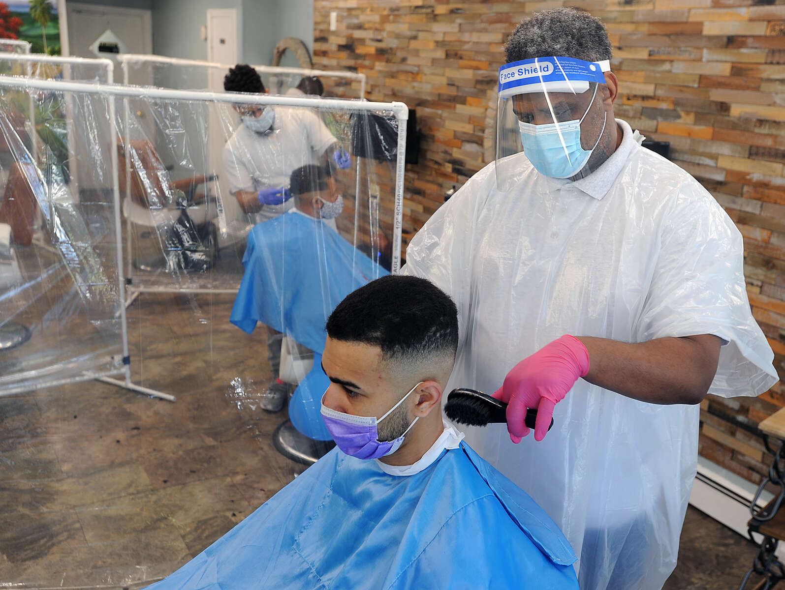 5/26/20-- FRAMINGHAM-- With plastic sheeting, gloves, masks, and faceshield, Papalote Estilo Barbershop owner Levi Bautista gives Rafael Chavez a haircut Tuesday, May 26, 2020 at the Waverly Street shop.  It was the first day the shop has been open since the coronaviorus pandemic began. [Daily News and Wicked Local Staff Photo/Art Illman]