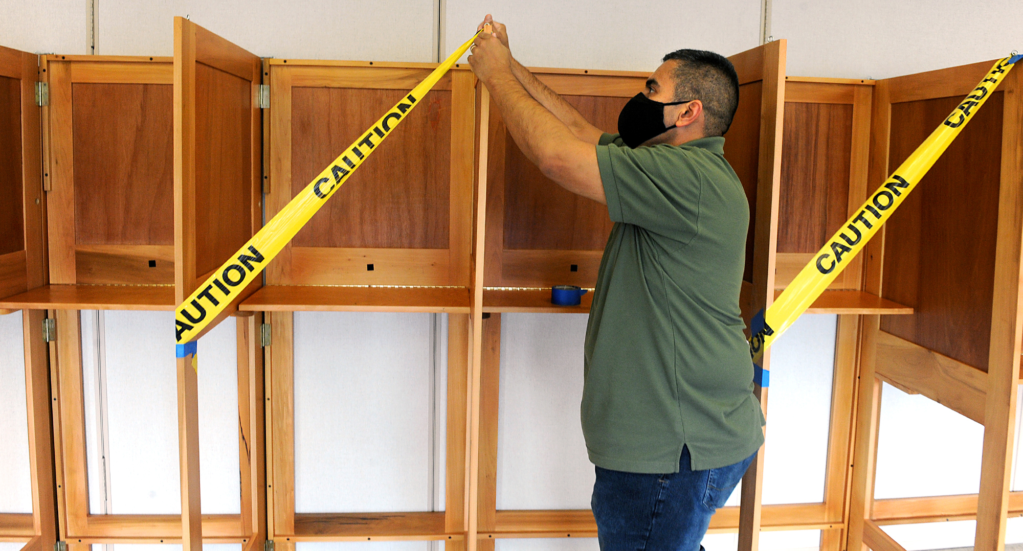 Marlborough Elections Clerk Leo Mercado tapes off every other voting booth Monday at the Senior Center voting place, getting ready for Tuesday’s election. [Daily News and Wicked Local Staff Photo/Art Illman]