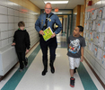 10/24/13-- MARLBOROUGH--  At Community Reader Day at the Jaworek Elementary School Thursday, Mass. State Police Lt. Jim Murphy, who's own children attended Jaworek, is escorted to the class of Becky Kaija by fourth graders Lucas Racki, left, and Malazhi Strothers. More than 30 community leaders read to students.  Murphy's book was What Does It Mean To Be Present, by Rana DiOrio.Daily News Staff Photo/Art Illman