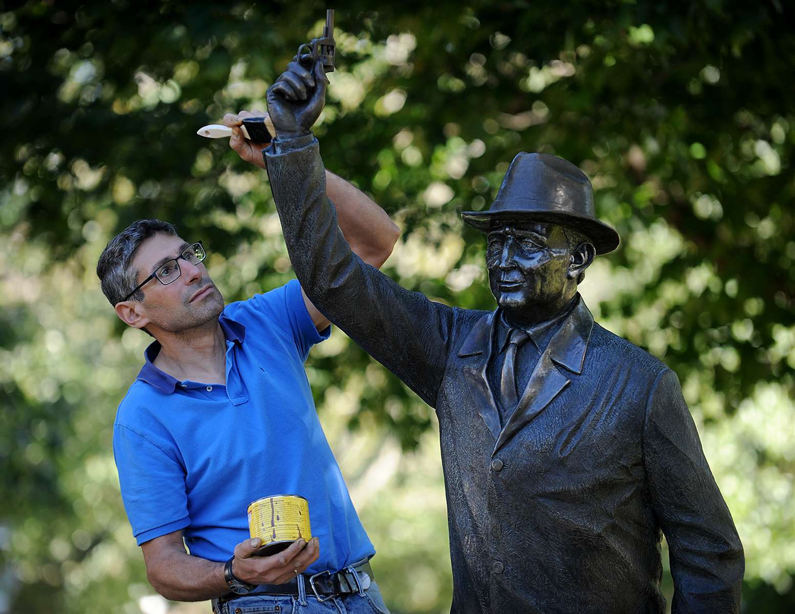 Hopkinton sculptor Michael Alfano applies wax to his sculpture, “The Starter,” honoring George V. Brown, Hopkinton’s “first citizen of sport,” October 6, 2021,  at the starting line of the Boston Marathon.  Alfano, who has also run the Marathon, spruces up his 2008 sculpture in advance of each race.  The 125th running of the Boston Marathon is Monday, October 11, 2021.