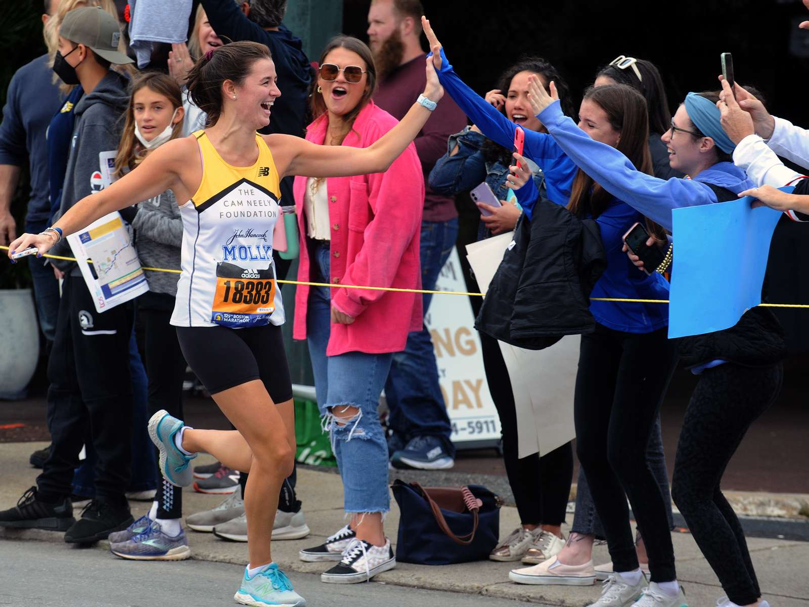 Molly Benson of Boston high fives supporters in Framingham during the running of the 125th Boston Marathon, Oct. 11, 2021.