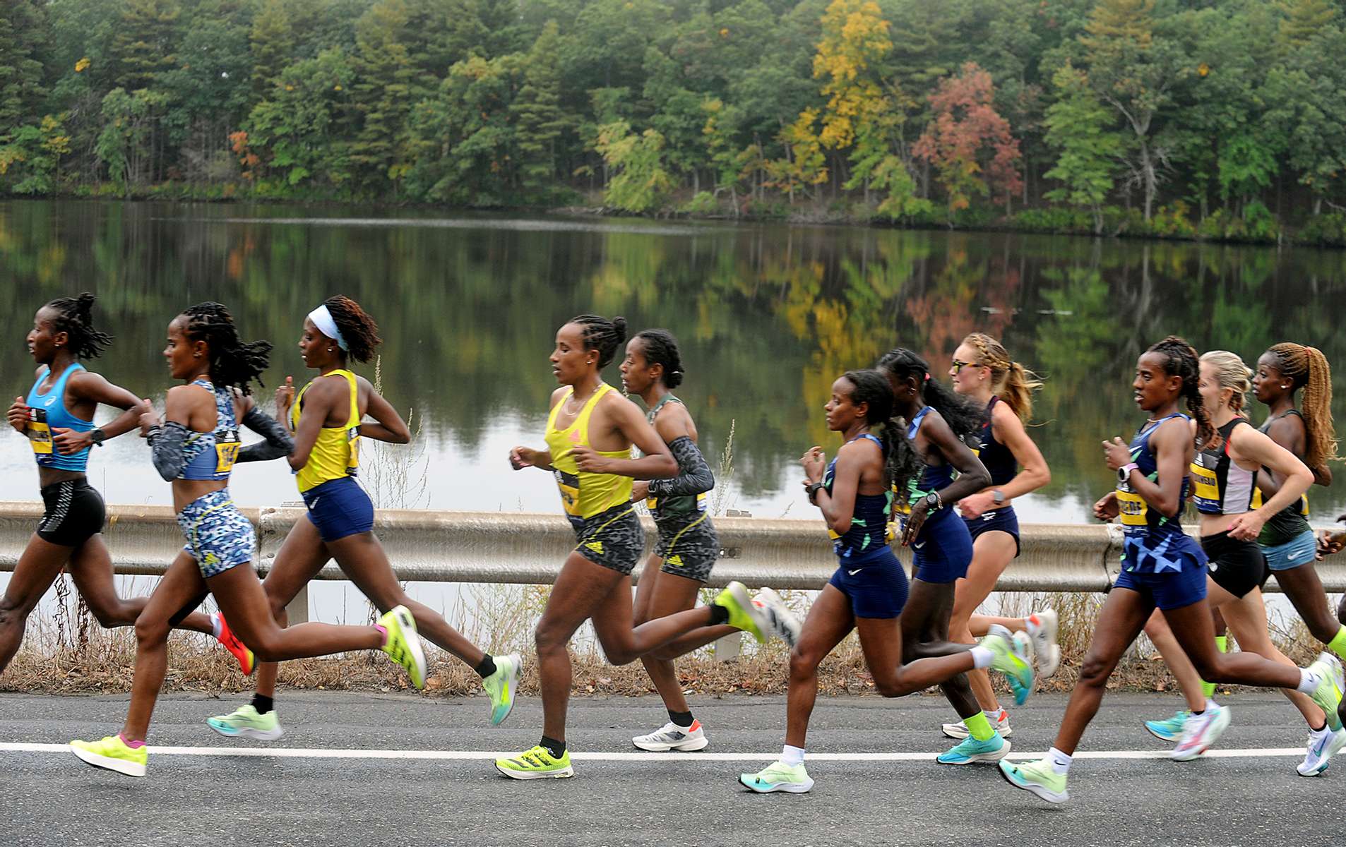 The lead pack of women runners pass Fisk Pond in Natick, during the running of the 125th Boston Marathon, Oct. 11, 2021.