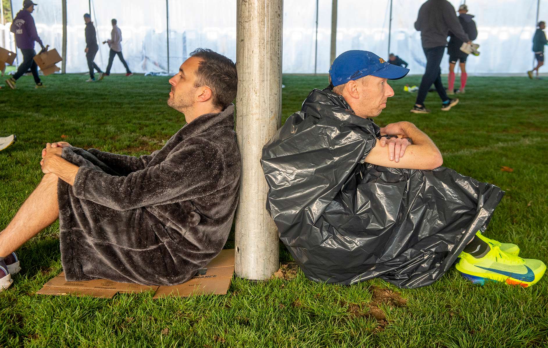 Thomas Adriaansen, of San Francisco, left, and Pat Wood, of St.Louis, rest, sharing a tent pole  in the Athlete's Village at Hopkinton High School  before the 128th running of the Boston Marathon, April 15, 2024.