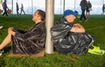 Thomas Adriaansen, of San Francisco, left, and Pat Wood, of St.Louis, rest, sharing a tent pole  in the Athlete's Village at Hopkinton High School  before the 128th running of the Boston Marathon, April 15, 2024.