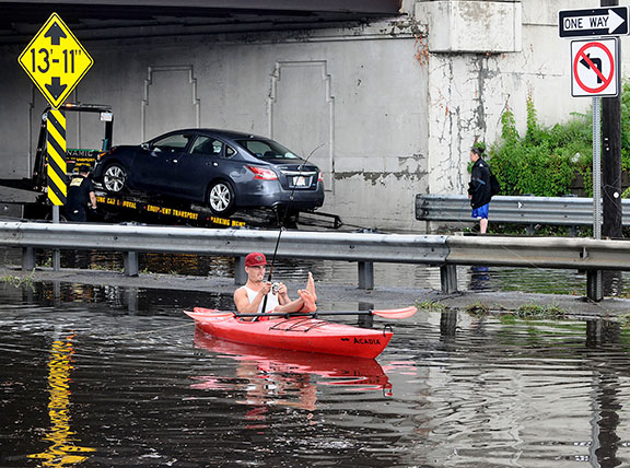 7/28/14-- FRAMINGHAM-- Patrick Primevara didn't miss the chance to kayak on Rte. 9 Monday morning in the eastbound lane, while in the westbound lane one of three stranded vehicles is towed from the water under the Rte.126 bridge. Torrential downpours caused ponding there Monday morning at about 9 a.m.  Traffic was stopped in both directions causing  backups for miles.Daily News Staff Photo/Art Illman