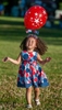 Sarah Matos, 2, of Framingham, enjoys the music and a balloon at the Stars and Stripes Over Framingham event at Farm Pond Park, June 28, 2024.