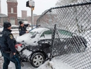 Framingham Police officers help to free a car that slid on the snow tand lodged through a chain link fence at Water Street and Central Street, with the Sudbury River a short distance away, Jan. 23, 2023. 