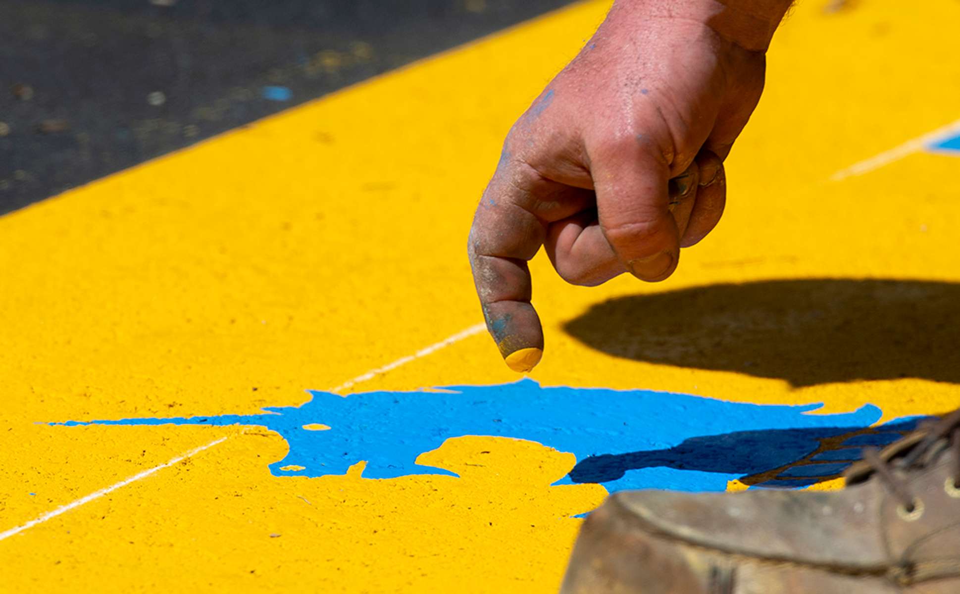 James Sawler of Road Safe Traffic literally puts the finishing touch on the  start line for the 127th running of the Boston Marathon on Rte. 135 in Hopkinton,  creating the unicorn's eyes with his fingertip, April 11, 2023.