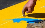 James Sawler of Road Safe Traffic literally puts the finishing touch on the  start line for the 127th running of the Boston Marathon on Rte. 135 in Hopkinton,  creating the unicorn's eyes with his fingertip, April 11, 2023.