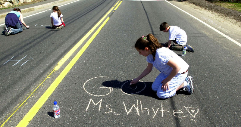 In 2003, Kayla Pacheco, 11, of Natick,  puts her support in writing for her dance teacher, Ms. Whyte along the race route in Ashland.