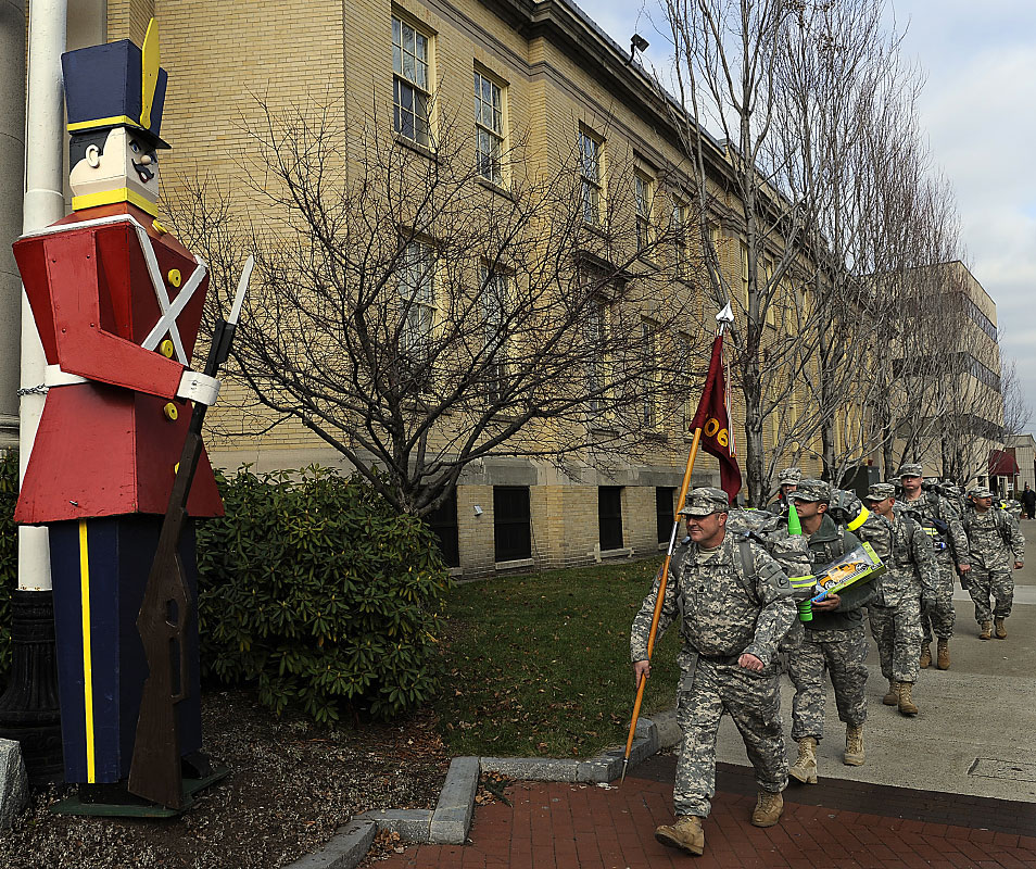 Army National Guard 1060th Transportation Company out of Framingham marched with toy filled backpacks down Concord Street to the Salvation Army headquarters Wednesday, delivering gifts for the Angel Tree Toy program. The toys will be distributed to families next week. Here they march past the Memorial Building and a Shoppers World Toy Soldier.