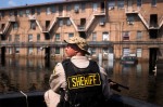 Bernalillo County Sheriff's Department Sgt. Paul Jacobs scans building after building of the besieged B.W. Cooper housing project buildings near downtown New Orleans from an air boat. He was searching for people to take out of the flooded area on Sept. 5. His boat floats on a mixture of water, gas, oil, sewage and mud.