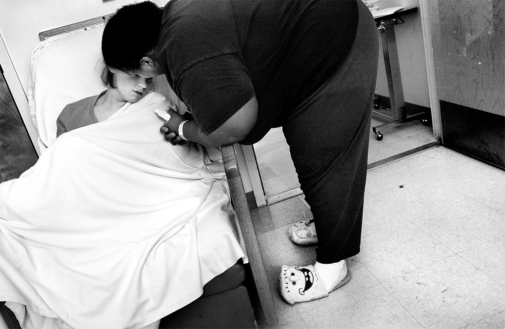 Pepa Robinson Rashad, gently coaxes her youngest daughter into putting medicine on her lips while at the hospital for treatment. For a time, Pepa wore Sponge Bob Square Pants slippers because they made her laugh. As Mooda's treatment stretched into months she wore out the slippers.