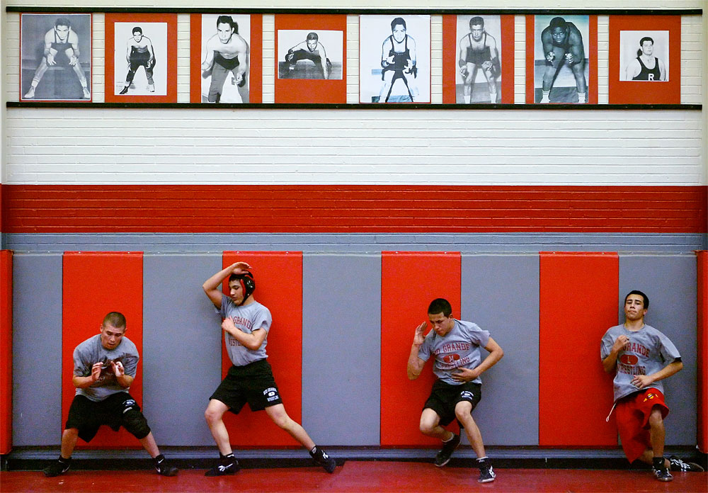 Underneath pictures of former Rio Grande High School state champion wrestlers, 2007 teammates, left to right, Charles Gallegos, Justin Vigil, David Romero and Fabion Griego, work to perfect their escape moves.