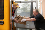 HYANNIS - Barnstable Public School food services worker Steve Kelley passes a box of meals to director Dave Badot, left, on Monday, March 23, 2020. The staff have been bagging breakfast and lunch for students on the free and reduced meal plan and then delivering them to various pick up sites.