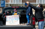 HYANNIS - Thiago DeOlivera helps adjust his 5-year-old son, Michael’s, mask while his other son Samuel, 8, and nephew, Nicholas, 8, hold a sign for hospital workers in the Cape Cod Hospital parking lot on Friday, April 10, 2020. 