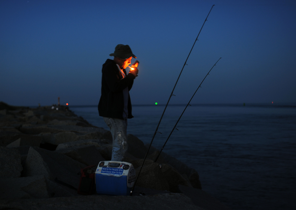 8:15 p.m. -- Chris Carey of Pembroke fishes for stripers on the Scusset Beach jetty on Tuesday, August 19, 2014. He said he would stay out there until 4 or 5 a.m. {quote}The excitement of actually catching a fish. You don't know how big it's gonna be or how good it is until you catch it and pull it in,{quote} he said of why he stay outs all night. {quote}You've got to put your time in. I've taken a nap before and gotten chowed by mosquitoes, a little breeze helps.{quote} He added that he smokes cigarettes to keep the pests away since he doesn't like bug spray.