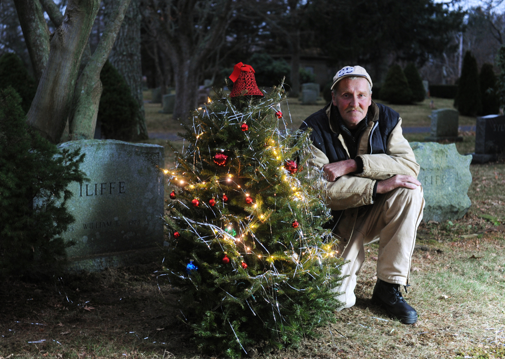 Charles Iliffe, 54, and his friends decorated a Christmas tree at the gravesite of Iliffe's brother, William, and mother, Peggy, at Beechwood Cemetery. The tradition of setting up the tree was started by Peggy and Charles after William's death in 1973. After a lapse due to Peggy's passing, Charles has renewed the tradition on Thursday, December 5, 2014.