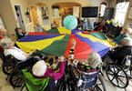 Dee Lawrence and Margaret O'Hara swat at the ball during therapeutic exercise session with the parachute at the JML Care Center. Federal cuts to Medicare reimbursement rates will impact nursing home facilities on the Cape. 