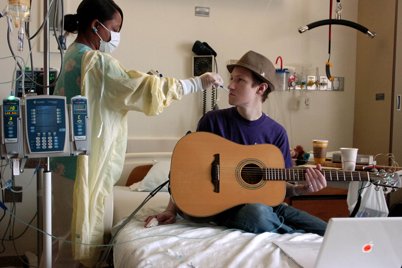 Emerson College student Matthew Starring, 23, takes a quick break from rehearsing his upcoming solo performance so personal care attendant Sherina Mayo can check his vital signs in his room on the 12th floor for oncology at Brigham and Women's Hospital on Friday, April 3, 2009. Matthew recently found out that his leukemia had relapsed for the second time after receiving a bone marrow transplant from his sister last summer and then being in remission for eight months.