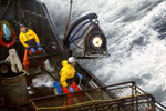 Crewman Lee Fleury prepares to throw the grappling hook at a crab pot buoy off in the distance while Lyndon Yockey (rear) runs the hydrolics to manuever heavy crab pots being stacked onboard. The 20003 Bristol Bay red king crab season lasted 5 days and 2 hours and was plagued with gale force winds of 35 knots or higher almost everyday causing to seas to rise 10 to 15 feet. (© copyright Karen Ducey)